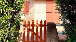 Un portón de madera roja que da a un edificio con techo de tejas.