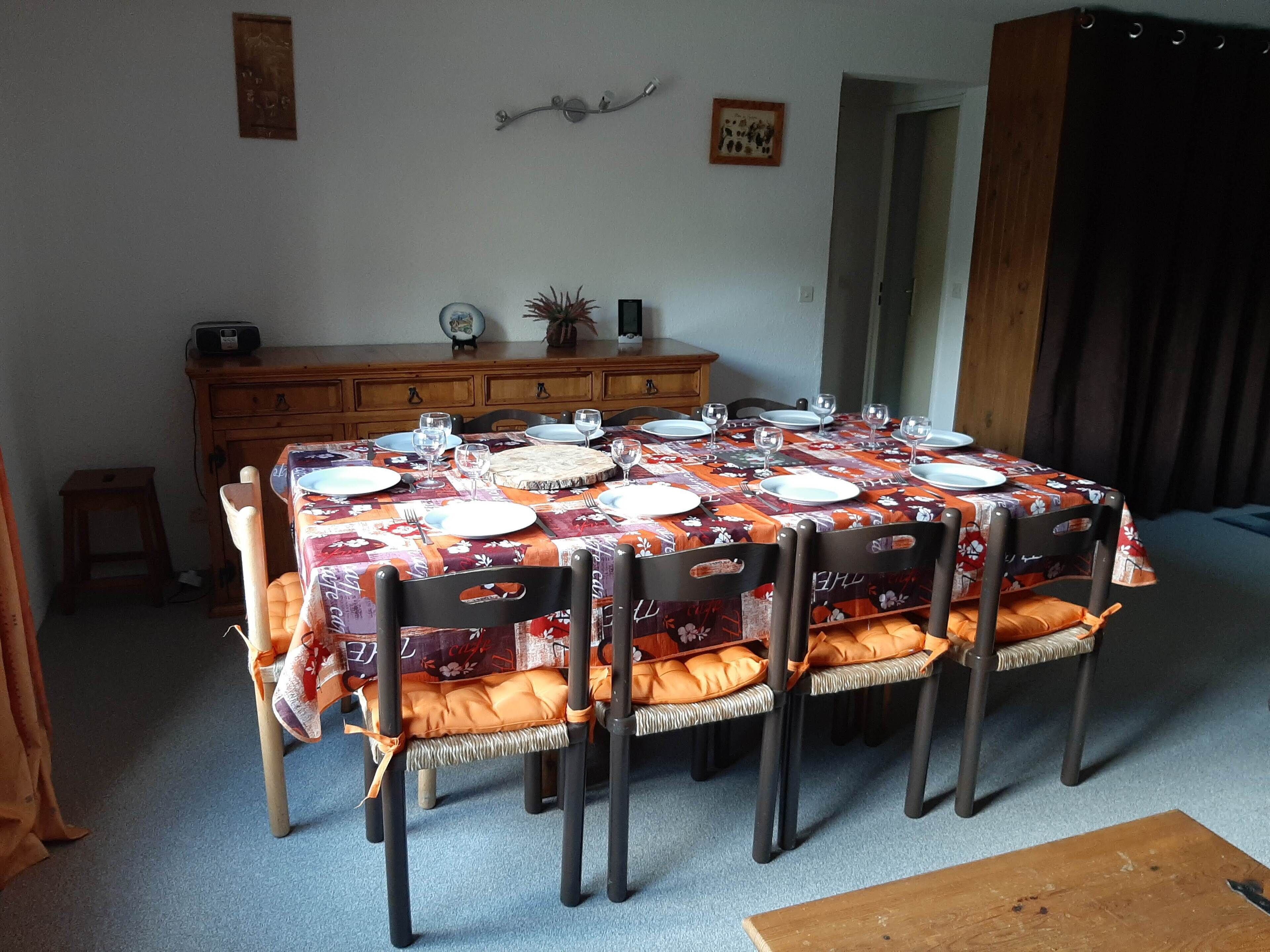 Een eetruimte met een tafel voor zes personen, omringd door stoelen met oranje kussens.