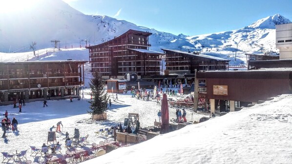 A ski resort with a wooden building, ski lifts, and a snowy mountain backdrop.