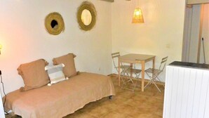 Ein gemütliches Zimmer mit einem Bett, einem kleinen Tisch und Stühlen. Zwei Wandbilder und eine Leuchte sind vorhanden.