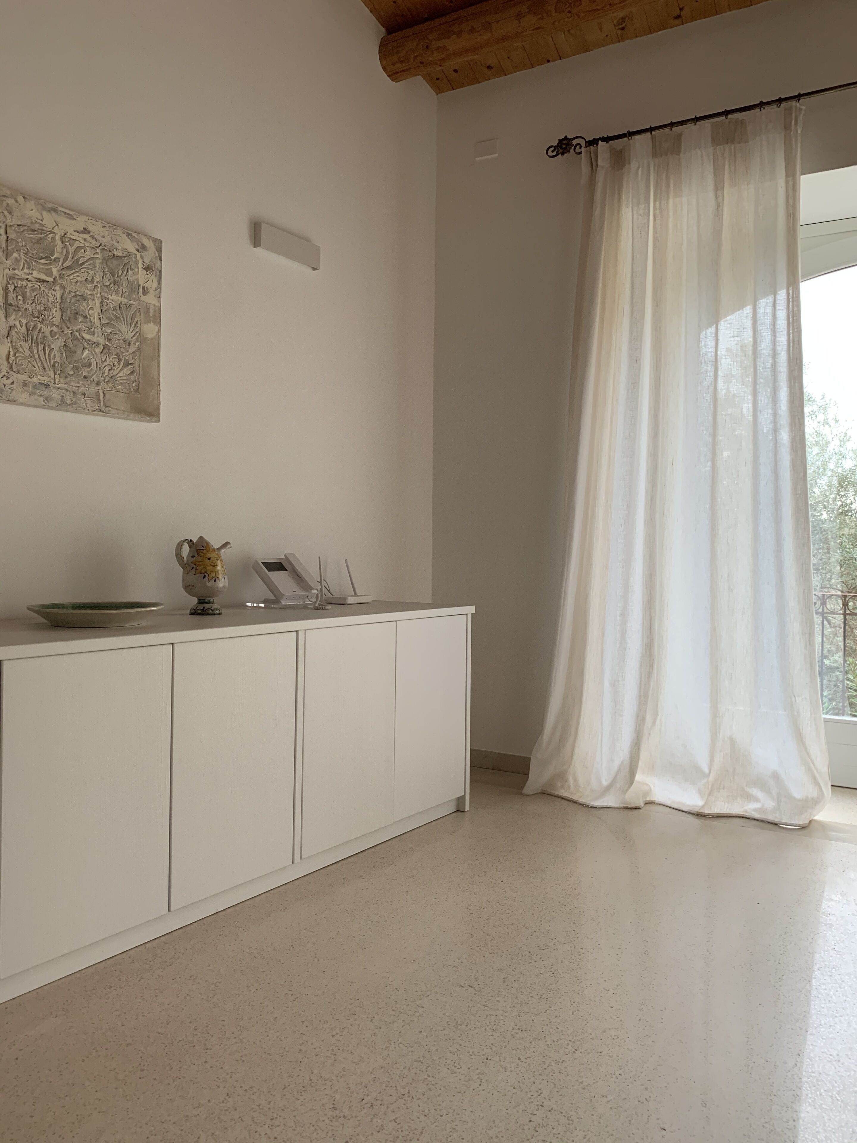 A minimalist room with a white cabinet, a decorative plate, and a wall art piece.
