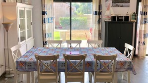 A dining area with a table set for four, chairs, a cabinet with glass doors, and a view through a glass door to the outside.