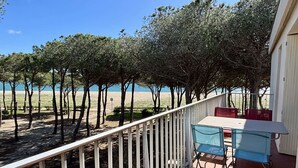 Un balcone con tavolo e sedie affacciato su una spiaggia e alberi.