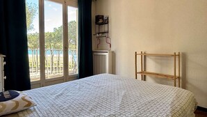 Una camera d'albergo con un letto, uno scaffale in legno, un termosifone e una finestra con tende.