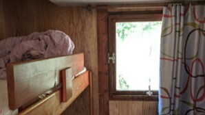 A small, compact room with a bunk bed, a single bed, and a window with curtains. - --- Mobile home n ° 17 --- (ESCARO)