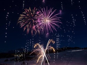 Un paisaje nevado con fuegos artificiales en el cielo.