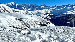 A snow-covered mountain landscape with ski trails and a chairlift.