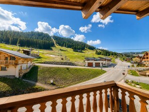 Un borgo montano con case in legno, cielo sereno e una strada che attraversa il villaggio.