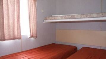 Une chambre avec deux lits simples, une fenêtre avec des rideaux et un lit superposé au-dessus.