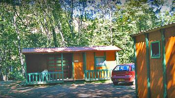 Une petite cabane avec une véranda et une voiture garée devant.