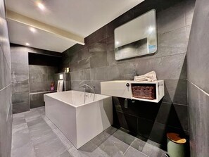 Ein modernes Badezimmer mit einer großen Badewanne, einem Waschbecken und einem Spiegel.