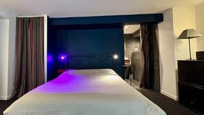 Quarto de hotel com uma cama grande, uma escrivaninha e uma luminária.