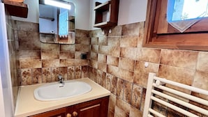 Un baño con lavamanos, espejo y perchero para toallas.