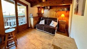 Una cabaña acogedora con interior de madera, un sofá, una cafetera y un balcón con vistas.