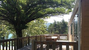 A wooden deck with a table and chairs, surrounded by trees and overlooking a body of water. - A corner of paradise: access lake side with exceptional view (Chorges)
