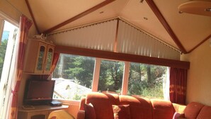 A cozy living room with a large window, wooden beams, and a television. - A corner of paradise: access lake side with exceptional view (Chorges)