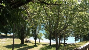 A park with trees, a picnic table, and a view of a body of water. - A corner of paradise: access lake side with exceptional view (Chorges)