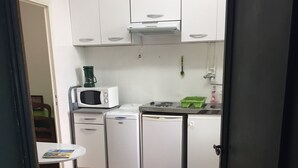 A compact kitchen with white cabinets, a microwave, a coffee maker, a sink, and a small dining table with chairs. - Studio old town 17m2, 1min from the sea (Menton)