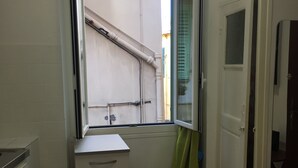A small, clean bathroom with a window, a sink, a cabinet, and a trash bin. - Studio old town 17m2, 1min from the sea (Menton)