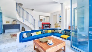 Una sala de estar moderna con un sofá seccional azul, una mesa de centro de madera y una escalera con barandillas azules.