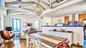 Una cocina amplia con una mesa de comedor de madera, sillas blancas y una isla grande con un fregadero.