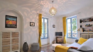 Una habitación con sofá, televisor, estantería y suelo estampado.