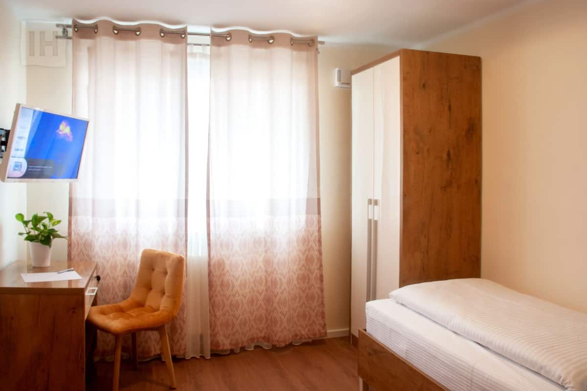 Ein Schlafzimmer mit einem Bett, einem Schreibtisch mit Stuhl und einem Fernseher.