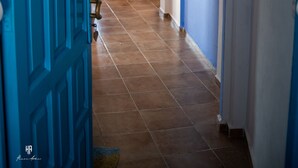 Un pasillo con una puerta azul, un tapete estampado y una zona de estar con cojines.