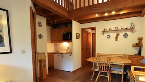 Une cuisine chaleureuse avec des meubles de rangement en bois, un réfrigérateur blanc et un coin repas comprenant une table et des chaises en bois.