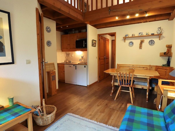 A cozy kitchen with wooden cabinets, a white refrigerator, and a dining area with a wooden table and chairs.