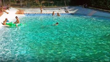 Une piscine à l’eau claire, entourée d’une plage.