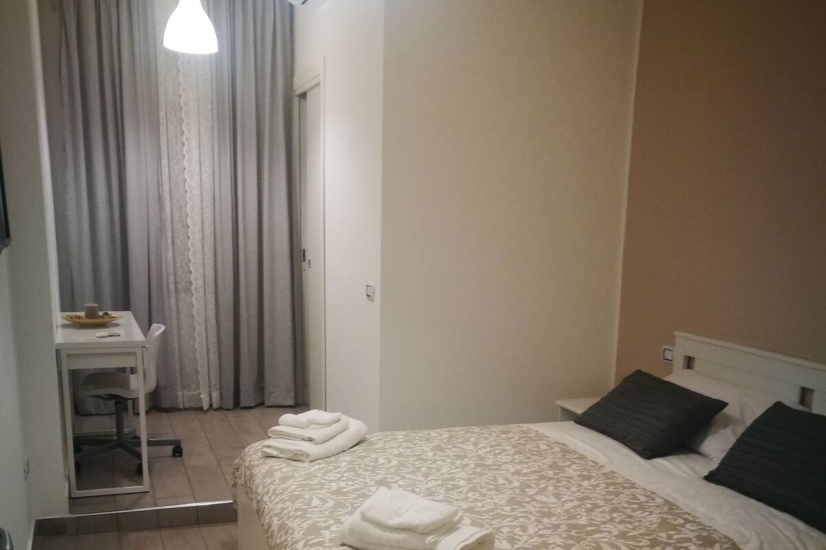 A hotel room with a bed, a desk, and a chair.
