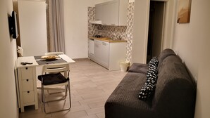 A compact living space with a kitchenette, a dining area, and a sofa. - 'O Vic' Stritt (Naples)