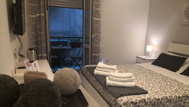A hotel room with a bed, a desk with a kettle, a small table with chairs, and a view of the outside balcony. - 'O Vic' Stritt (Naples)