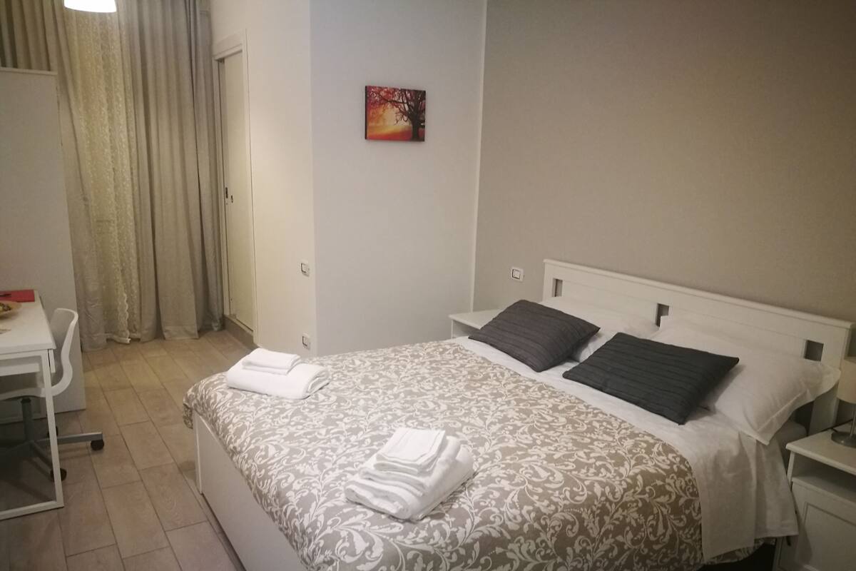 A neatly arranged hotel room with a bed, a desk, and a chair.