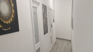 A hallway with white walls, wooden flooring, and doors with glass panels. - 'O Vic' Stritt (Naples)