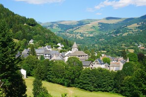 A village with traditional stone buildings, surrounded by lush greenery and rolling hills.