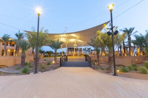 A hotel entrance with a covered walkway, palm trees, and street lamps.