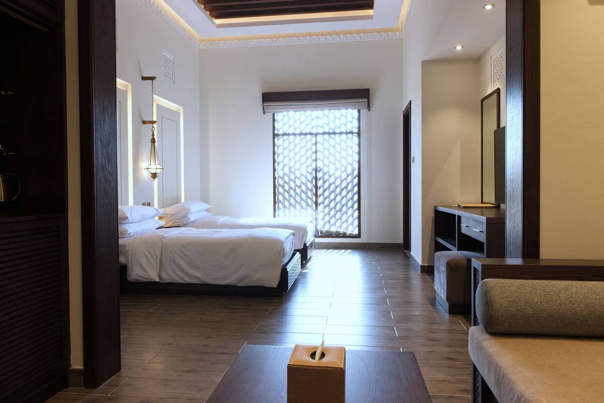 Habitación de hotel con cama, sofá, televisión y ventana con vista.
