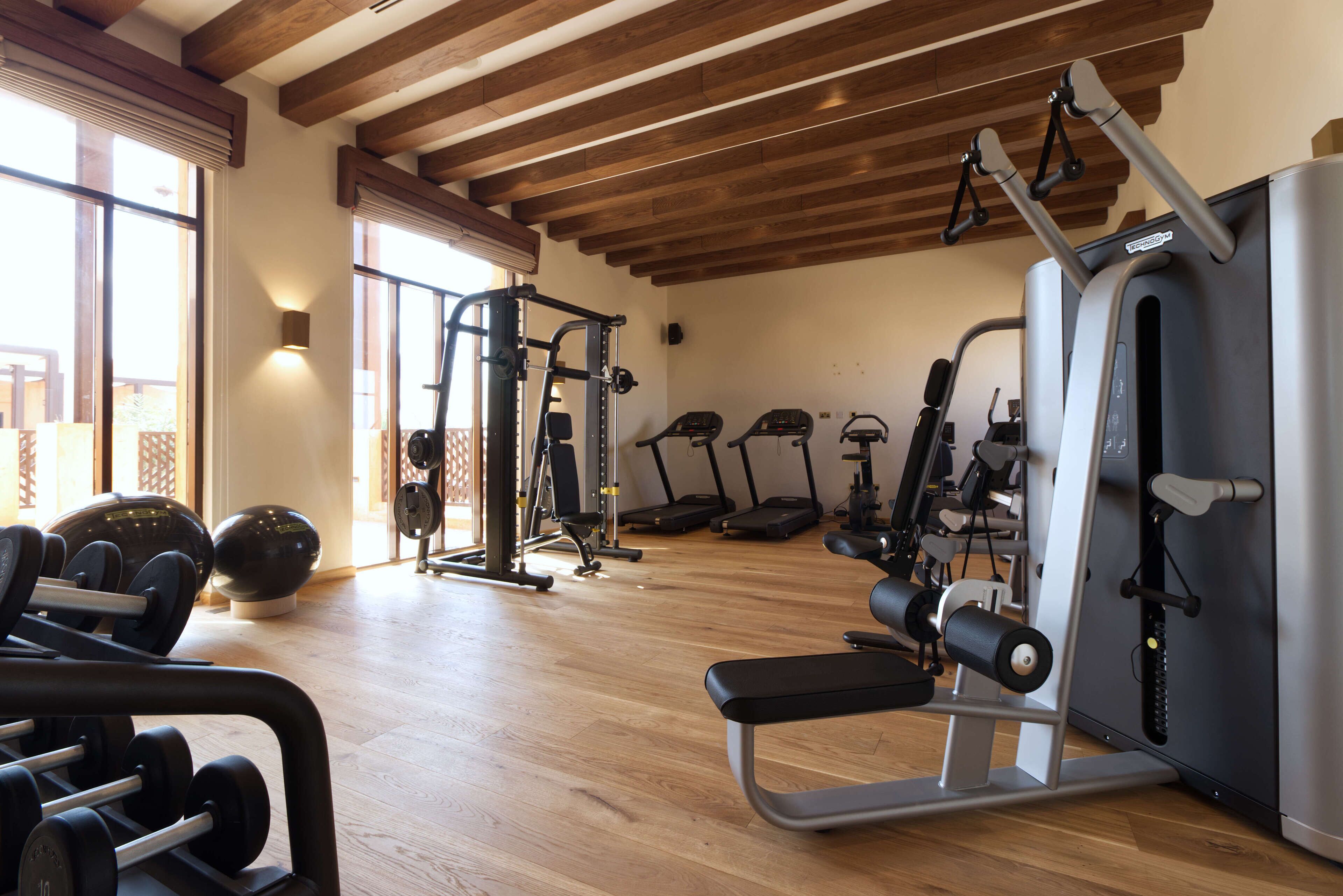 Un gimnasio con varios equipos de ejercicio, incluyendo mancuernas, una banca y máquinas de cardio.
