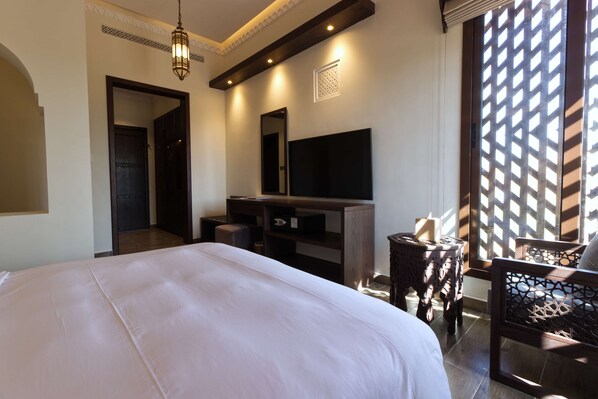Une chambre d’hôtel avec un grand lit, un téléviseur à écran plat, un bureau et une chaise.