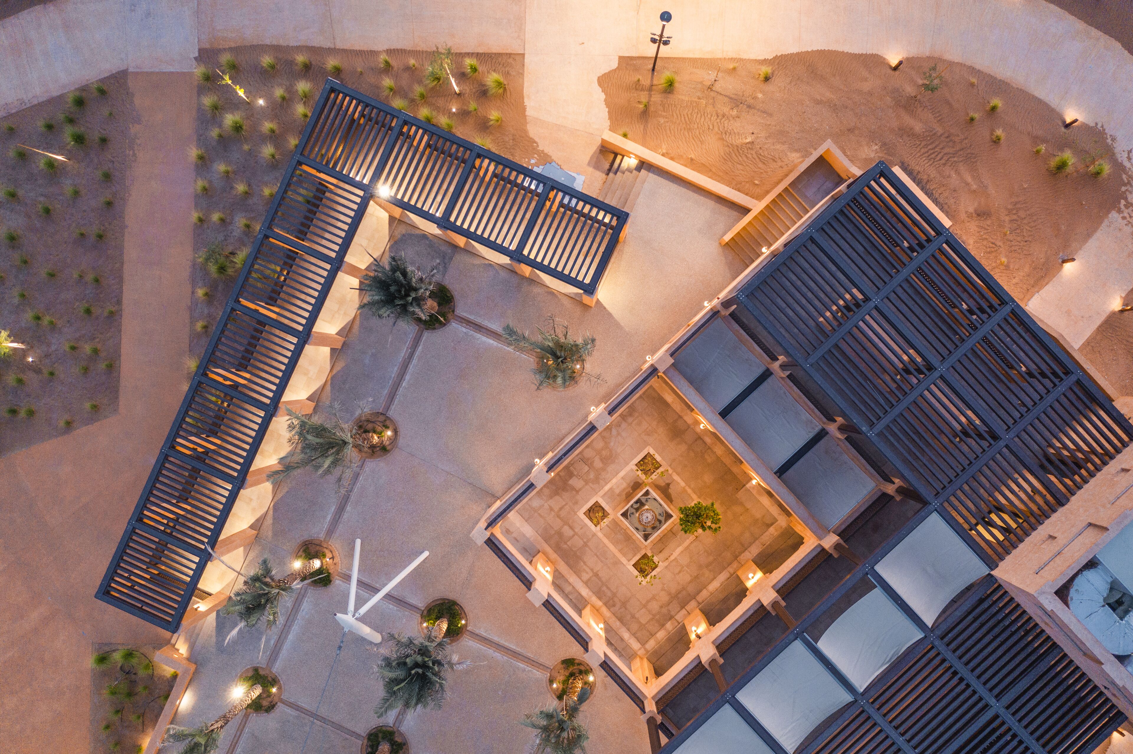 An aerial view of a courtyard with a central seating area, surrounded by plants and a water feature.
