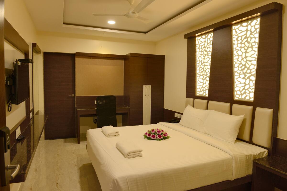 A hotel room with a bed, a desk, a chair, and a television.