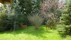 Un espace extérieur verdoyant agrémenté de trois sculptures de cerfs en bois.