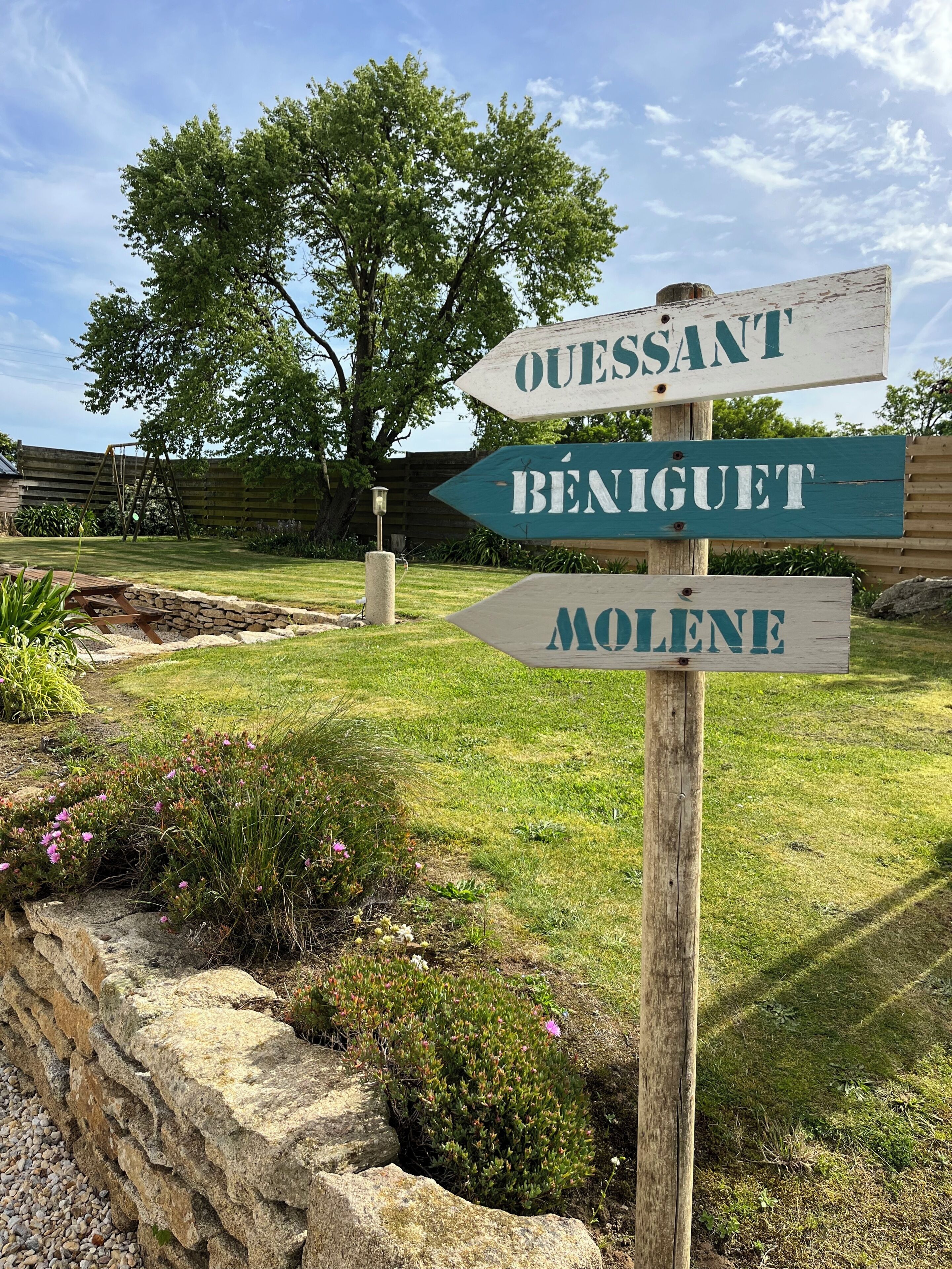 Un poste de madera con flechas direccionales que señalan a 'OUESTANT', 'BENIGET' y 'MOLENE'.