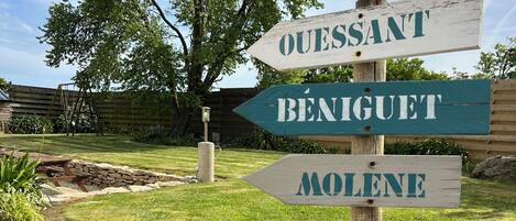 Un poste de madera con flechas direccionales que señalan a 'OUESTANT', 'BENIGET' y 'MOLENE'.