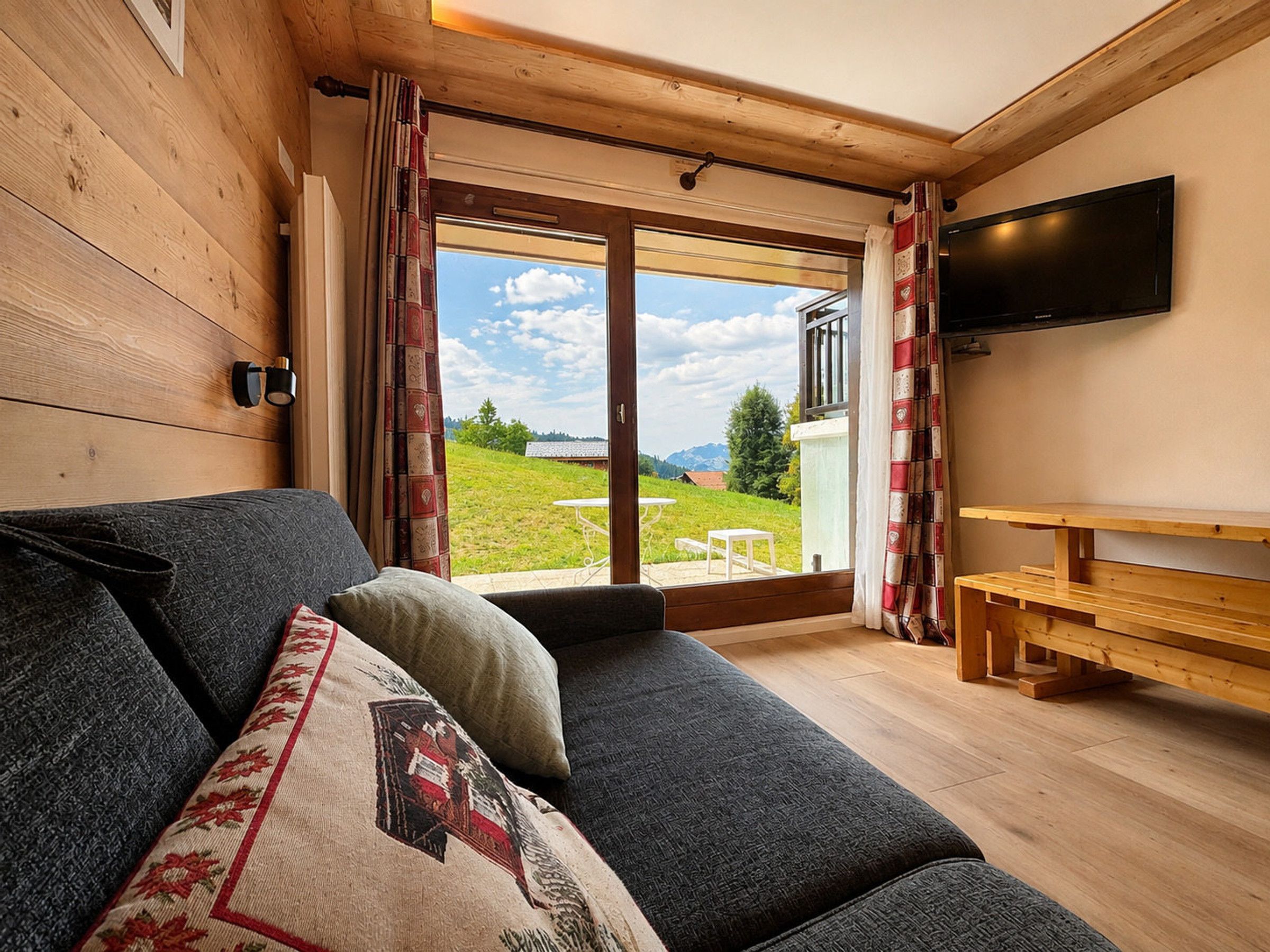A cozy room with a sofa, a flat-screen TV, and a wooden bench.