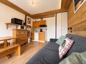 A compact living space with a kitchenette, a wooden bench, a sofa with a decorative pillow, and a wooden ceiling. - Quiet studio with garden and terrace in Notre-Dame-de-Bellecombe (Notre-Dame-de-Bellecombe)
