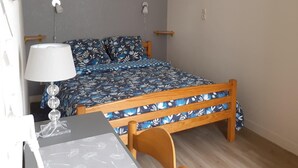 Quarto com cama, mesa de cabeceira, abajur, prateleira na parede e uma obra de arte na parede.