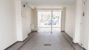 A hallway with a patterned floor, a gate at the end, and a wall-mounted light fixture.